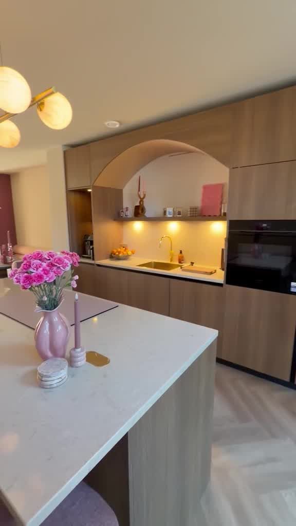 Keukeneiland met marmeren werkblad en bloemen, met doorkijk naar de keuken met boogvormige nis in Schiedam